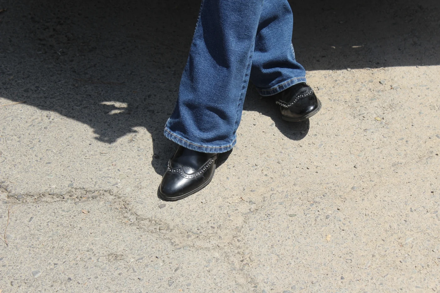 Close study of shoes stepping on sunlit pavement