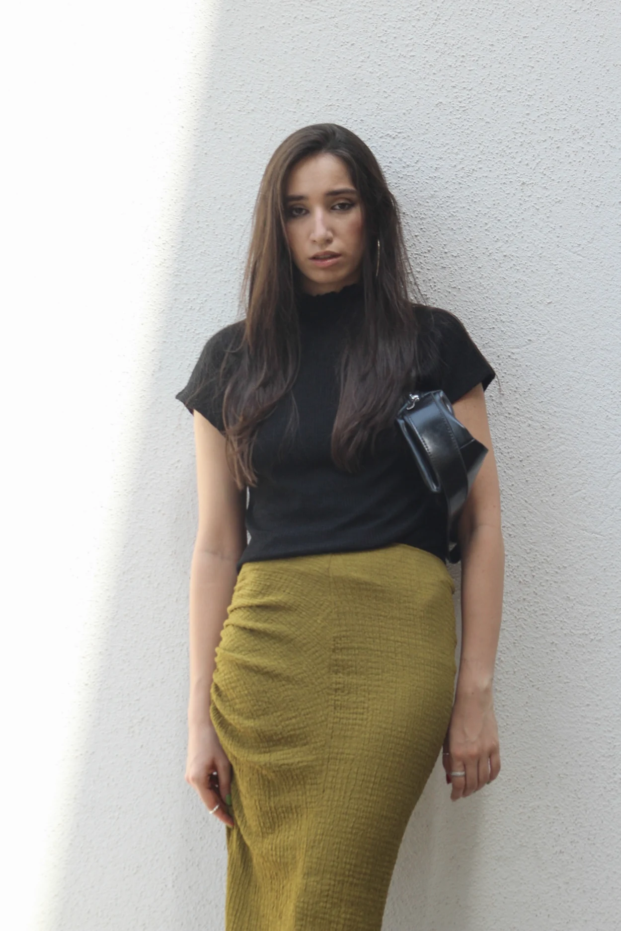Editorial portrait against a pale textured wall